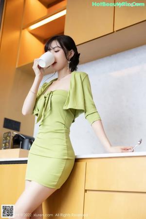 A woman in a green dress sitting on a chair.