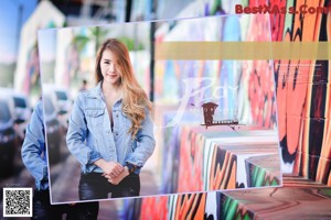 A woman sitting on the ground in front of a graffiti covered wall.