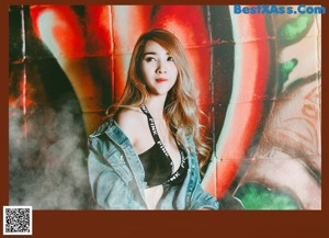 A woman sitting on the ground in front of a graffiti wall.