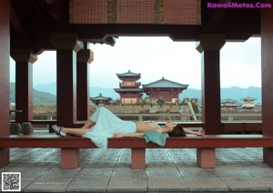 A woman laying on top of a bed next to a pillow.