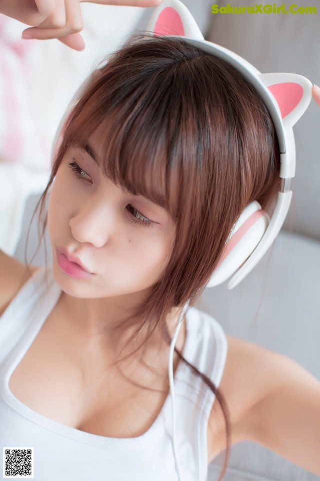 A woman wearing a pair of white headphones with pink ears.