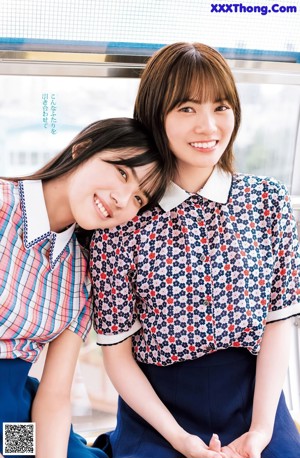 A couple of women sitting next to each other on a blue bench.