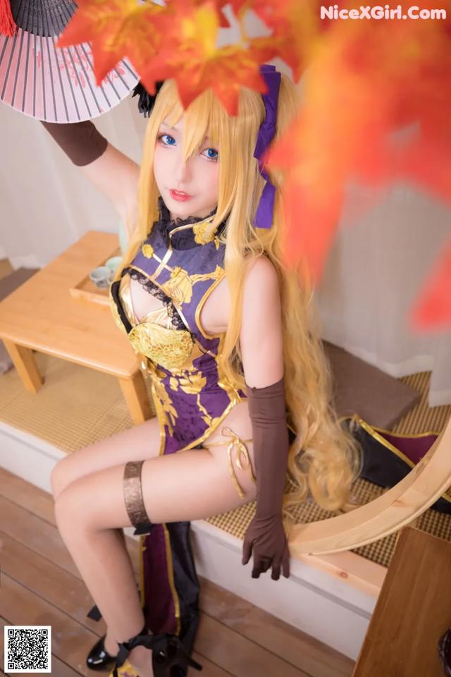 A woman in a purple and gold outfit holding a fan.