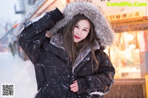 A woman in a green bodysuit and a black jacket in the snow.