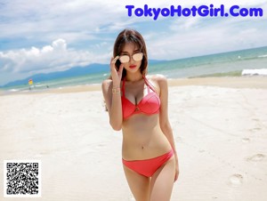 A woman in a white bikini and a white hat by a pool.