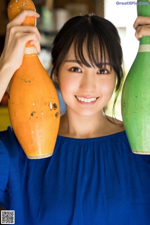 A woman in a blue dress holding a lemon on her head.