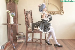 A woman with blue hair is sitting on a bed.