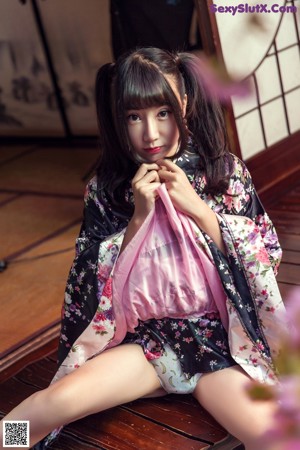 A woman in a kimono sitting in front of a window.