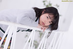 A young woman in a school uniform sitting on the floor.