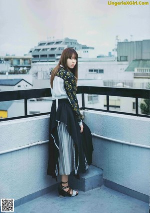 A woman standing on top of a building next to a window.