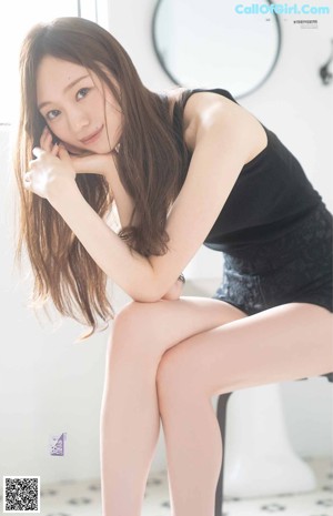 A woman sitting on a green chair with her legs crossed.
