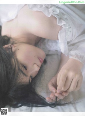 A woman laying on a bed in a white dress.