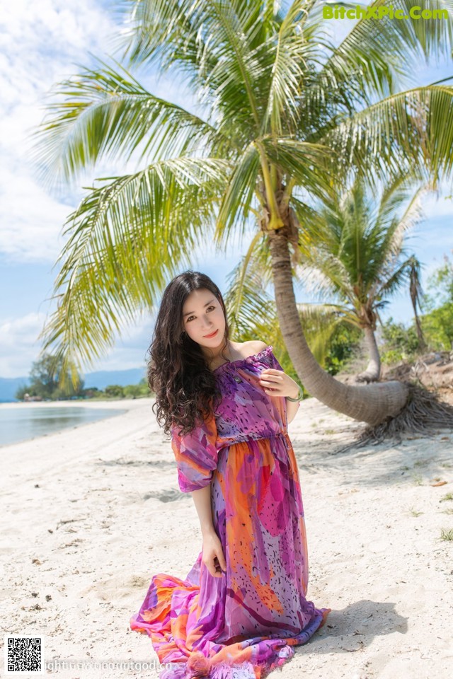 A woman in a colorful dress standing on a beach.