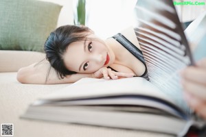 A naked asian woman leaning against a wall.