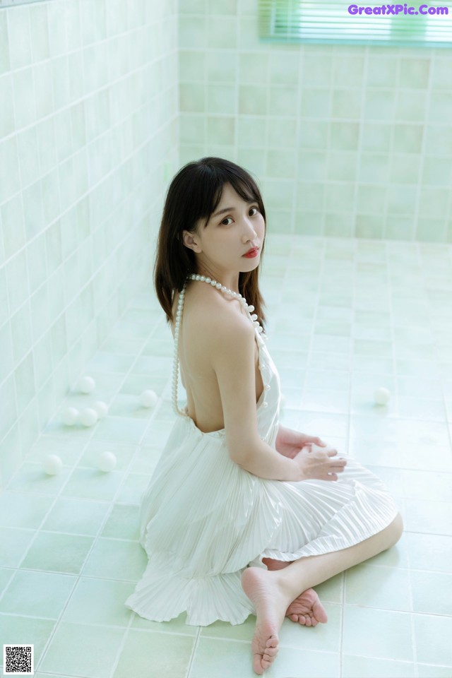A woman in a white dress sitting on the floor.