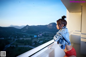 A naked woman sitting on a chair on a balcony.