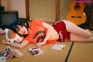 A woman in an orange shirt and red shorts posing for a picture.