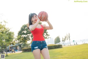 A woman sitting on a bench with a basketball.