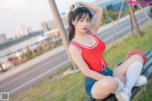 A woman sitting on the grass holding a basketball.