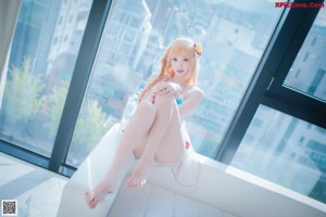 A woman in a white lingerie sitting on a window sill.