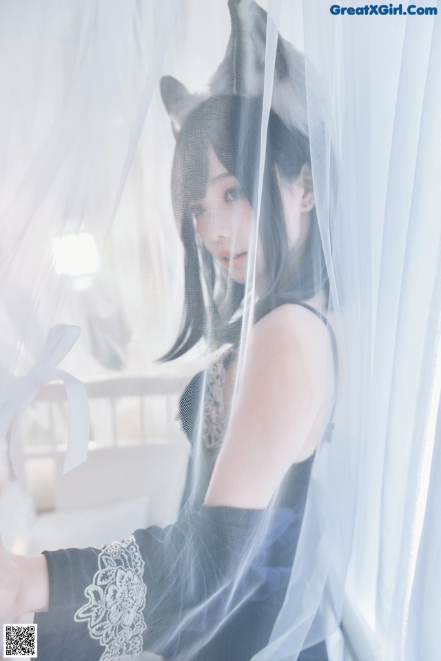 A woman in a black dress with a cat ears on her head.