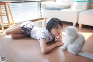 A woman sitting on a couch holding a white cat.