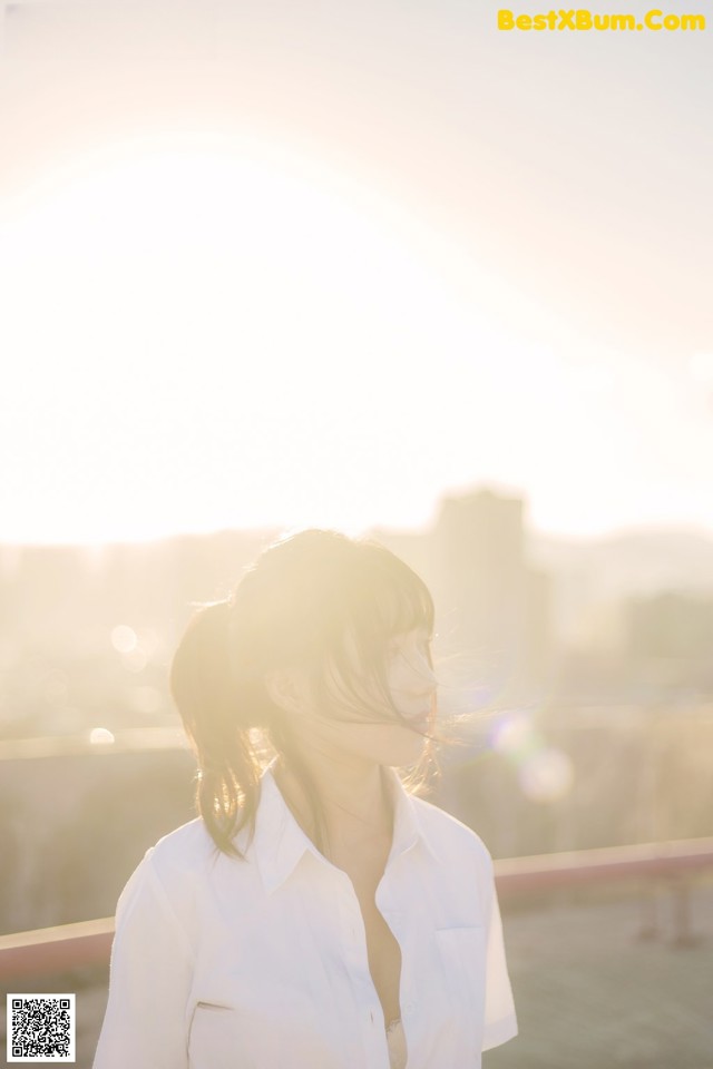 A woman in a white shirt standing on top of a roof.