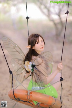 A woman in a green dress sitting on a tree branch.