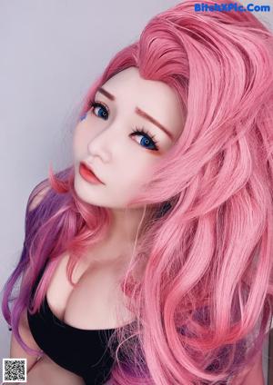 A woman with long pink and purple hair is posing for a picture.