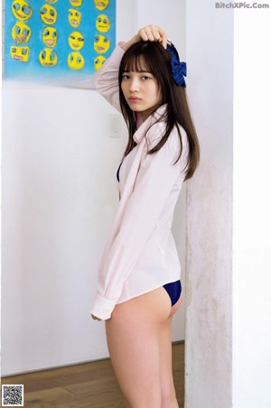 A woman in a pink shirt and blue panties posing for a picture.