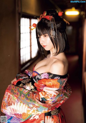 A woman in a black and gold kimono sitting on the floor.