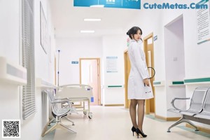 A woman in a white lab coat sitting on a hospital bed.