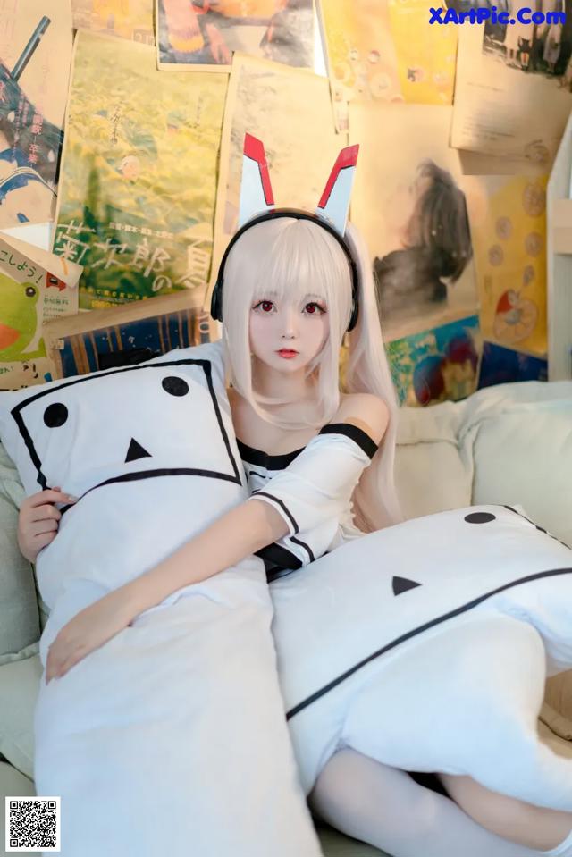 A woman sitting on top of a couch next to a pillow.