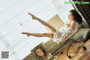 A woman sitting on a chair in front of a painting.