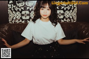 A woman in a white shirt and black stockings posing on a couch.