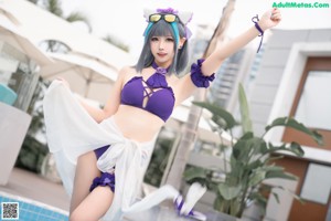 A woman in a purple bikini standing next to a pool.