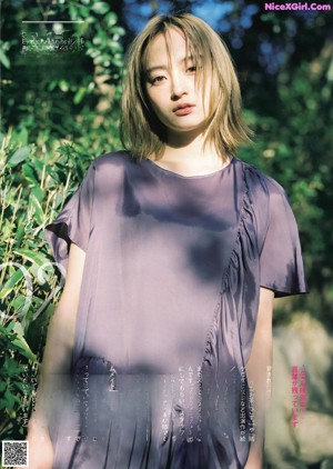A woman in a purple shirt is posing for a magazine.